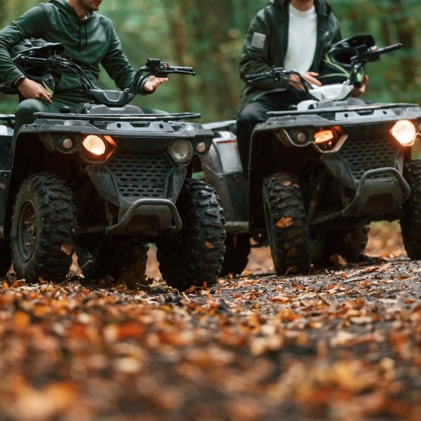 Two male atv riders is in the forest together